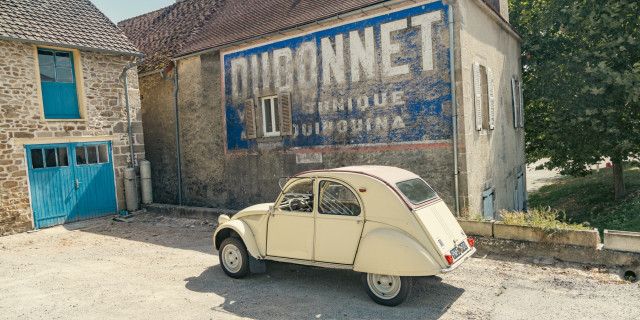 2cv AZ parked beside a house with painted Dubonnet wall sign
